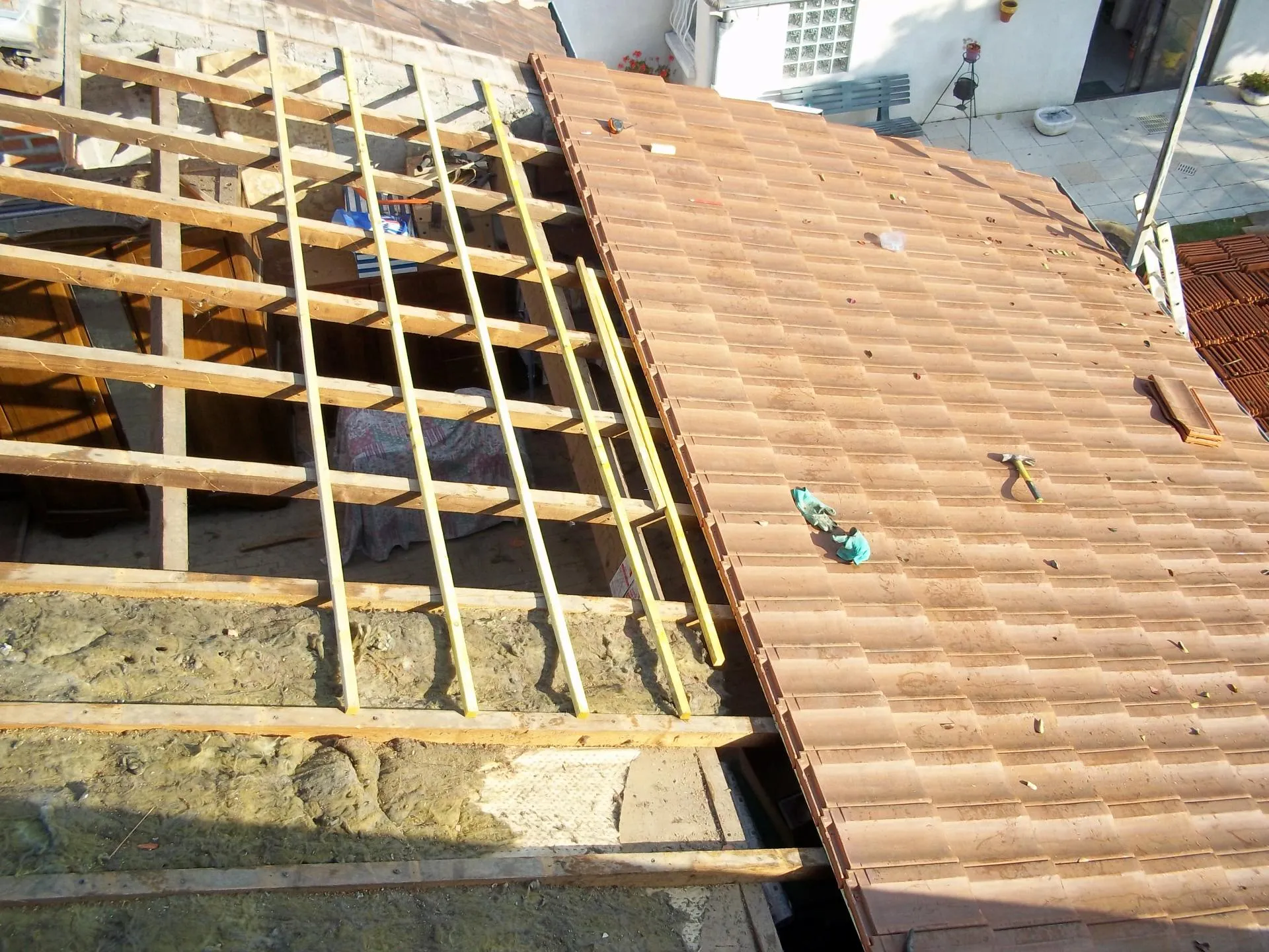 Pose de tuiles neuves sur liteaux pendant une réfection de couverture